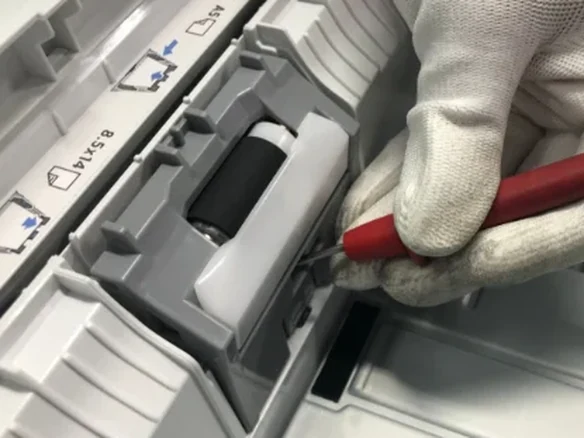 Technician repairing a printer's paper feed roller on site